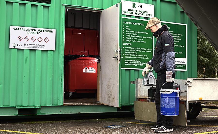 Kuvassa asiakas asioi vihreällä vaarallisten jätteiden keräyskontilla, jonka seinässä on ohjeet siitä, mitä jätettä konttiin voi tuoda